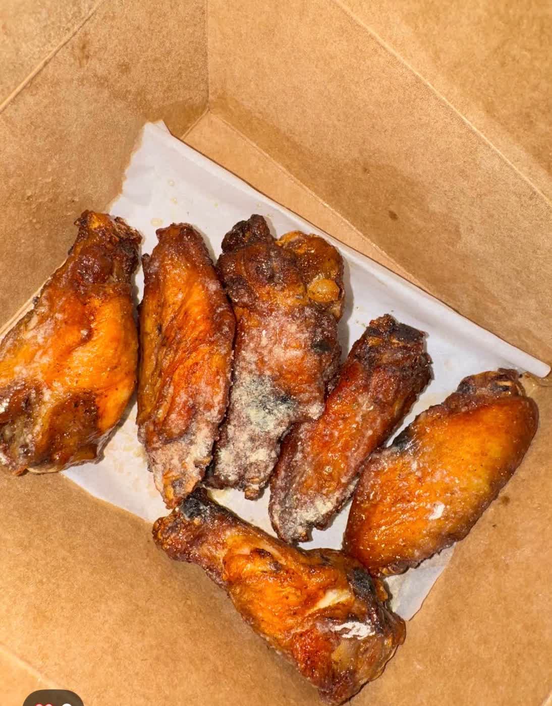 Six seasoned magic wings in a takeout box